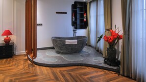 A modern bathroom with a freestanding bathtub, a red lamp, and a vase with red flowers.