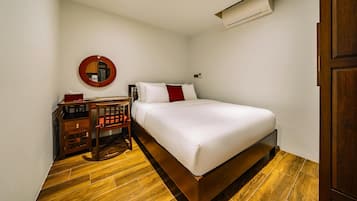 A bedroom with a bed, a desk, a chair, and an air conditioning unit.
