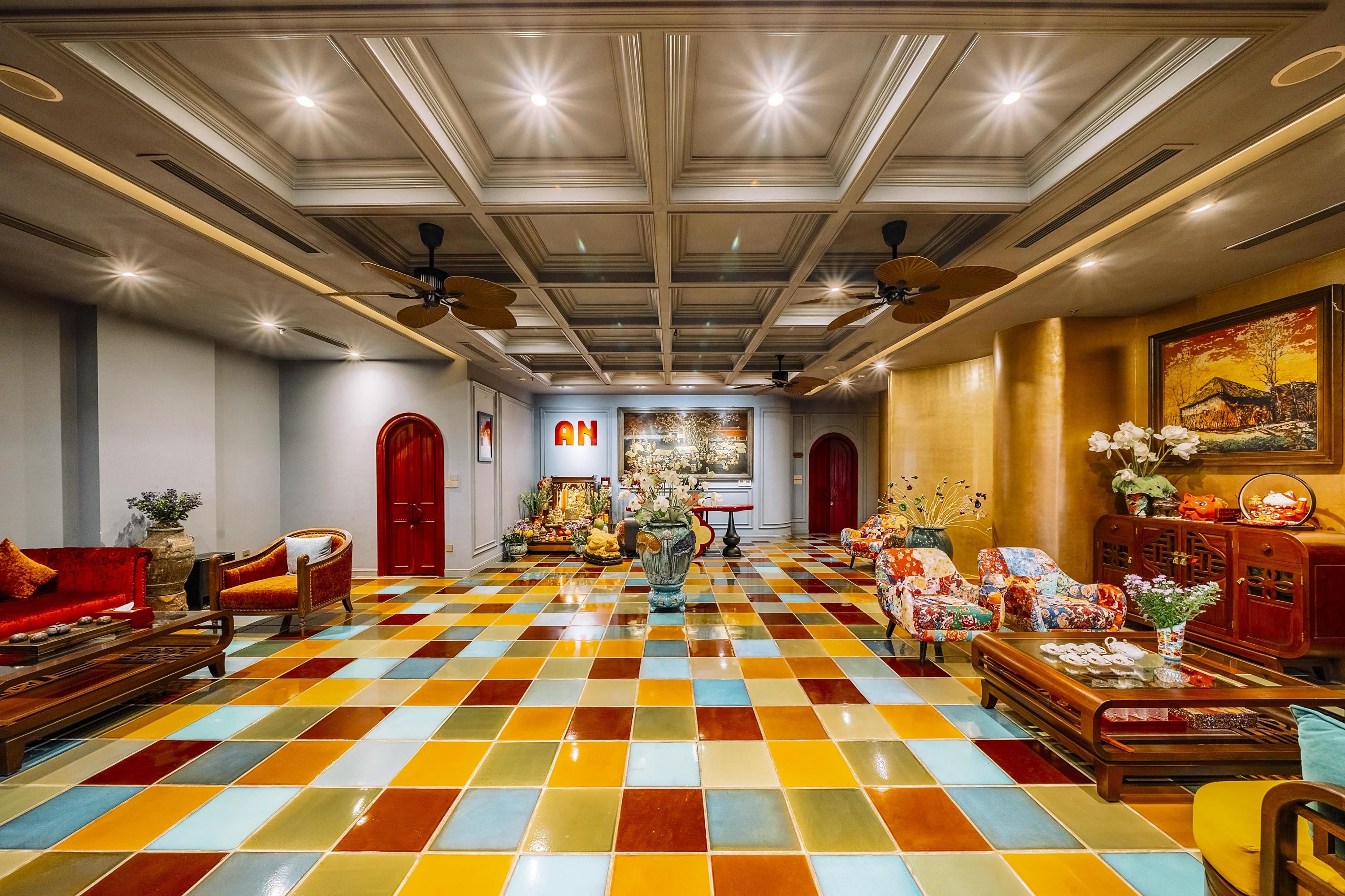 A hotel lobby with a checkered floor, red sofas, a chandelier, and ceiling fans.