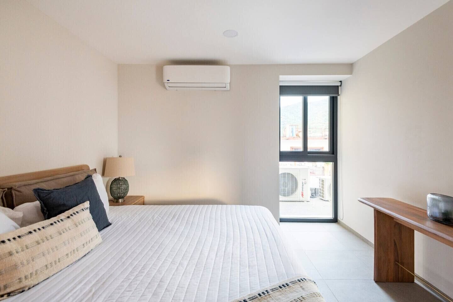 Une chambre d’hôtel équipée d’un lit, d’une lampe de chevet, d’une fenêtre et d’un appareil de climatisation.