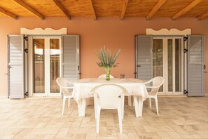 An outdoor dining area with a table, chairs, and a vase of flowers. - Nikorina Apts | 2 (Apolpena)