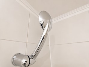 A chrome showerhead mounted on a white tiled wall. - MainMaint Espacio 3 (Santiago)