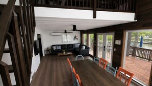 Zona pranzo con tavolo e sedie in legno, una scala e vista sull'esterno.