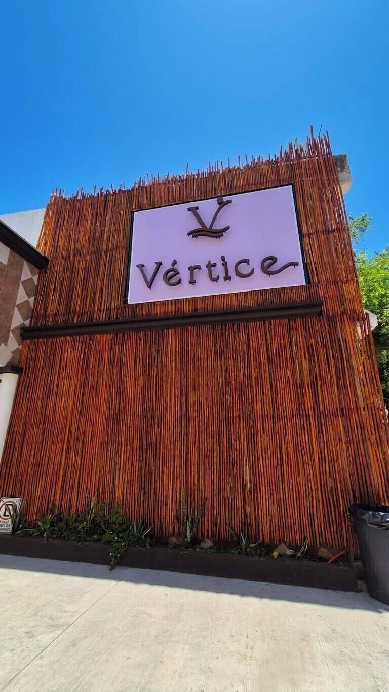 A sign with the word 'Vertice' on a bamboo wall.