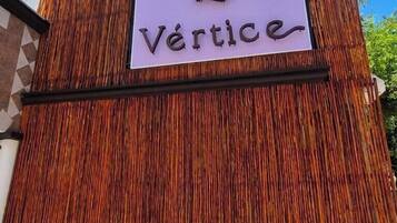 Un letrero con la palabra 'Vertice' en una pared de bambú.