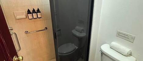 Ein kleines Badezimmer mit Toilette, Duschkabine und Waschbecken mit Seifenspendern.