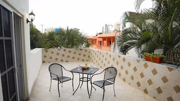 Un balcon avec une table et des chaises, un sol carrelé et un mur orné de motifs.