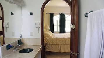 Un baño con lavamanos, espejo y toallero.