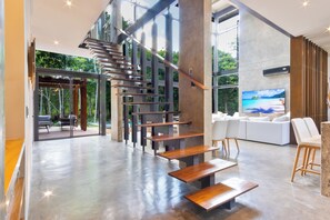 A modern interior with a wooden staircase, a large window, and a white sofa. - Luxury Jungle Villa - 4 Bedrooms - Private Pool and Cenote in a gated community (Puerto Morelos)