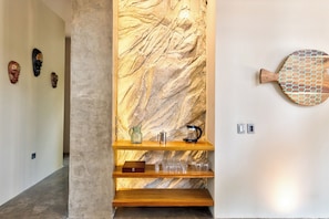 A hallway with a marble wall, wooden shelves with items, and a fish-shaped wall decoration. - Luxury Jungle Villa - 4 Bedrooms - Private Pool and Cenote in a gated community (Puerto Morelos)