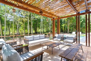 An outdoor patio with a wooden pergola, white sofa, and wicker chairs. - Luxury Jungle Villa - 4 Bedrooms - Private Pool and Cenote in a gated community (Puerto Morelos)