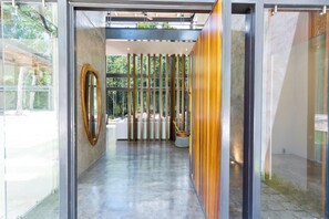 A modern interior with a glass door, a wooden wall, and a concrete floor. - Luxury Jungle Villa - 4 Bedrooms - Private Pool and Cenote in a gated community (Puerto Morelos)
