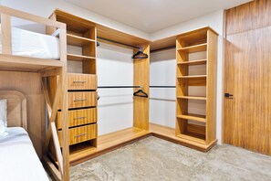 A walk-in closet with wooden shelving, a hanging rod, and a bed with a white mattress. - Luxury Jungle Villa - 4 Bedrooms - Private Pool and Cenote in a gated community (Puerto Morelos)