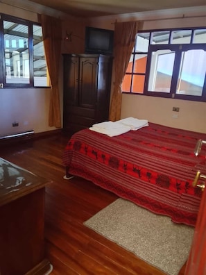 Una habitación con cama, un escritorio de madera, un armario y un televisor.