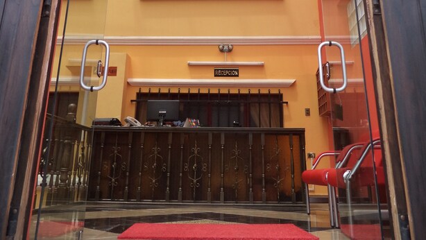 Entrada do Apart Hotel Turquesa, com balcão de recepção e tapete vermelho.