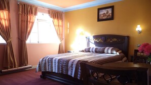 Quarto com cama, mesa de cabeceira, cadeira, mesa, abajur e um quadro na parede.