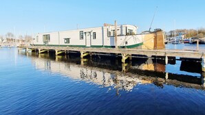A stationary houseboat docked at a marina with a clear sky. - Historic Houseboat Stay for 7 (Naarden)