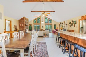 Eine geräumige Küche mit Essbereich, Holzbalken an der Decke und großen Fenstern.