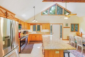 Eine Küche mit Holzausbau, einem Edelstahlkühlschrank, einer großen Kochinsel und einem Deckenventilator.