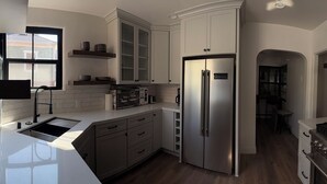 A modern kitchen with a stainless steel refrigerator, a gas stove, and white cabinetry. - Historic 3-bedroom house on Main st  in charming Sutter Creek (Sutter Creek)