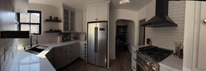 A modern kitchen with a stainless steel refrigerator, a gas stove, and white cabinetry. - Historic 3-bedroom house on Main st  in charming Sutter Creek (Sutter Creek)