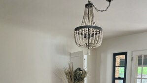 A dining area with a round table, six chairs, a chandelier, and a vase with dried plants. - Historic 3-bedroom house on Main st  in charming Sutter Creek (Sutter Creek)