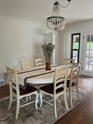A dining area with a round table, six chairs, a chandelier, and a vase with dried plants. - Historic 3-bedroom house on Main st  in charming Sutter Creek (Sutter Creek)