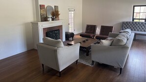 A living room with a fireplace, two sofas, a coffee table, and a large window. - Historic 3-bedroom house on Main st  in charming Sutter Creek (Sutter Creek)