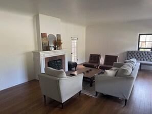 A living room with a fireplace, two sofas, a coffee table, and a large window. - Historic 3-bedroom house on Main st  in charming Sutter Creek (Sutter Creek)