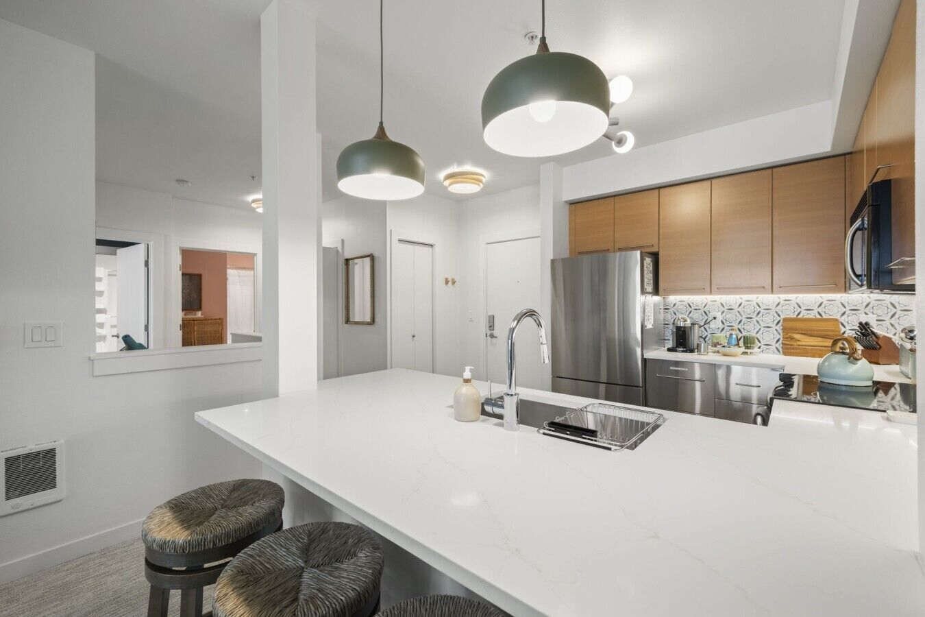 A modern kitchen with a large island, stainless steel appliances, and pendant lighting.