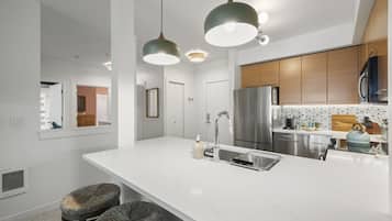 A modern kitchen with a large island, stainless steel appliances, and pendant lighting.