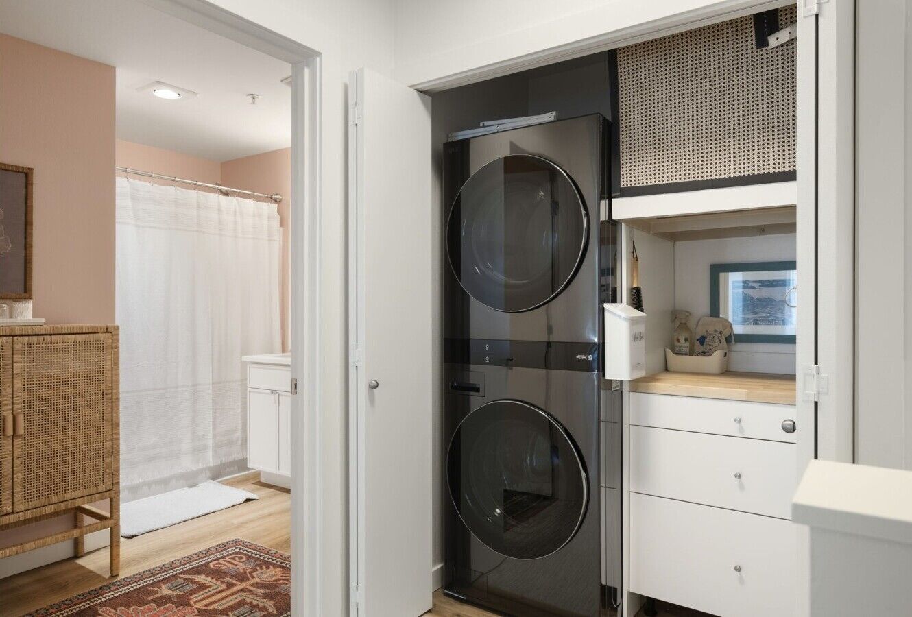 A laundry room with two washing machines, a drying rack, and a white cabinet with drawers.
