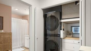 A laundry room with two washing machines, a drying rack, and a white cabinet with drawers.