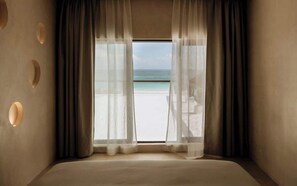 A room with a large window, a bed, and a view of the beach. - Beach Home with Chef - Butler - Pool & Sun Deck (Tulum)