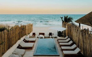 Un espace piscine avec des chaises longues et vue sur l’océan.