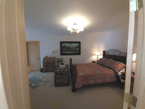 A bedroom with a bed, bedside tables, a nightstand, a lamp, a picture on the wall, and a door. - A private apartment on six acres, with a view no other listing in Gardiner has. (Gardiner)