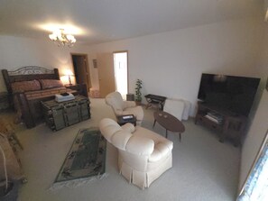 A living room with a sofa, armchair, small table, and a television. - A private apartment on six acres, with a view no other listing in Gardiner has. (Gardiner)