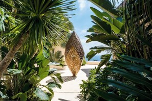 Un jardín tropical con una escultura geométrica, palmeras y un cielo despejado.