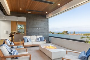 Ein modernes Wohnzimmer mit Kamin, einer Sofagarnitur und Meerblick.