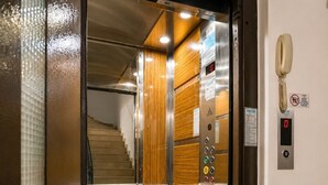 Un ascensor con paneles de madera en su interior, una pantalla digital y un teléfono instalado en la pared.