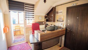 Une cuisine de taille réduite, avec un plan de travail en bois, une chaise rouge et une horloge au mur.