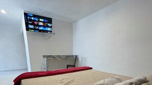 Ett hotellrum med en säng, en tv som är monterad på väggen och ett skrivbord med en stol.