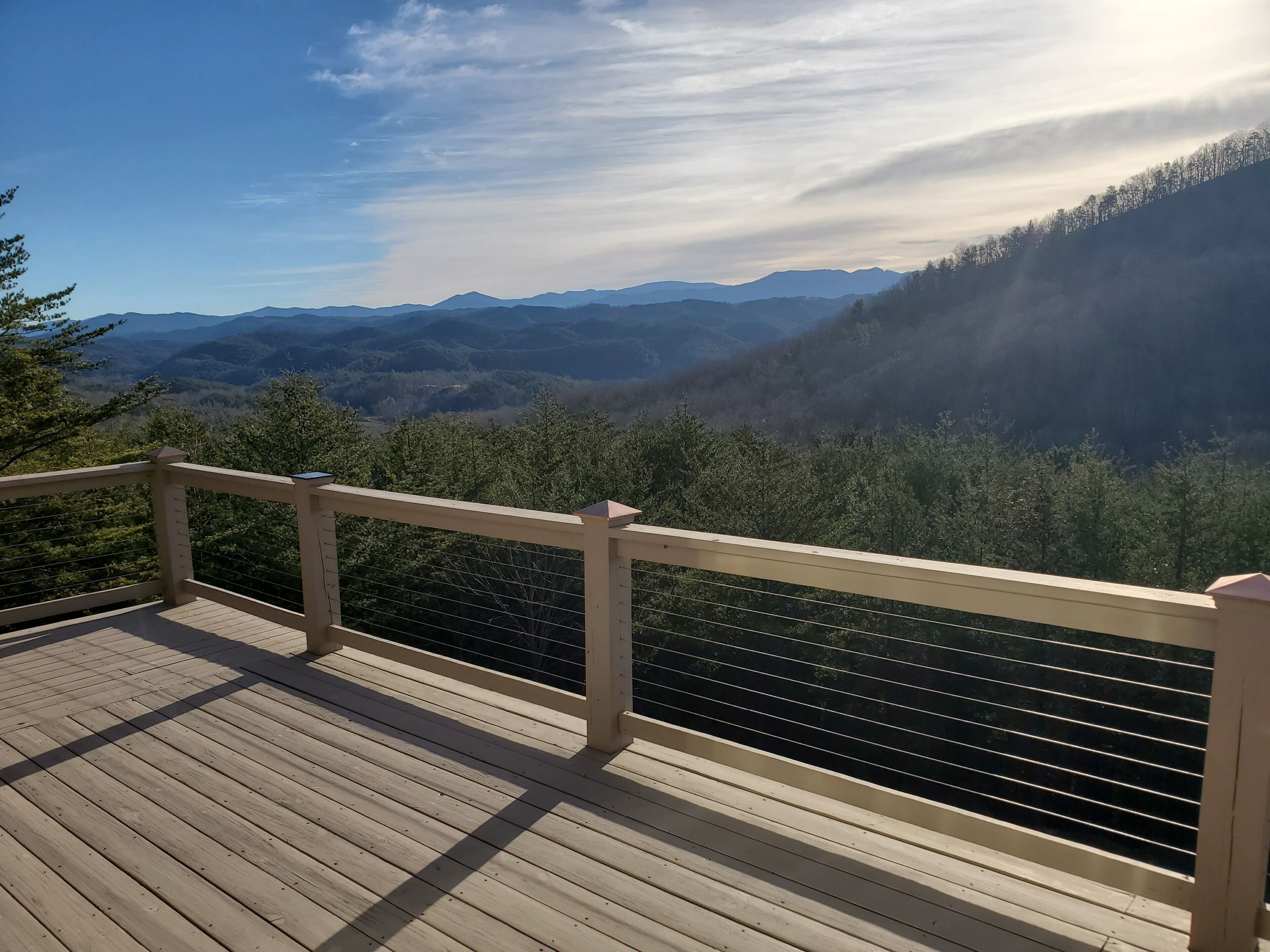 A wooden deck with a railing overlooking a mountainous landscape.