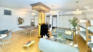 Uma sala de estar com mesa de pingue-pongue, sofá, mesa de centro e televisão.