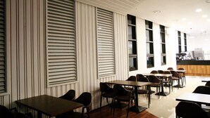 A modern restaurant interior with high ceilings, vertical blinds, and a long counter with seating. - Cordelia Hotel Geoje (Geoje)