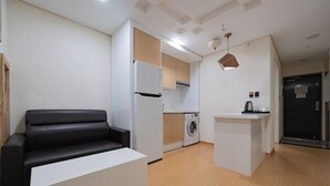 A compact living space with a sofa, a washing machine, a refrigerator, and a kitchenette. - Cordelia Hotel Geoje (Geoje)