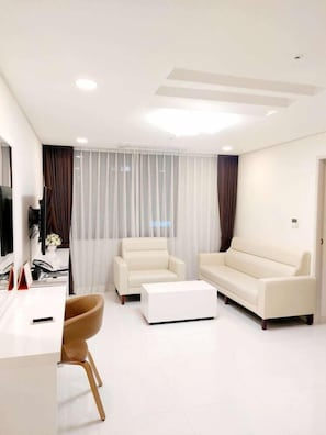 A modern living room with a sofa, coffee table, and TV stand. - Cordelia Hotel Geoje (Geoje)