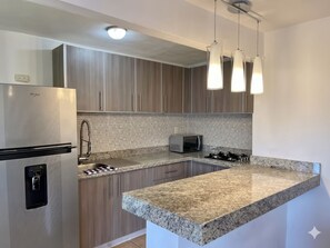 Eine moderne Küche mit einem Edelstahl-Kühlschrank, einer Mikrowelle, einem Gasherd und einem Wasserspender.