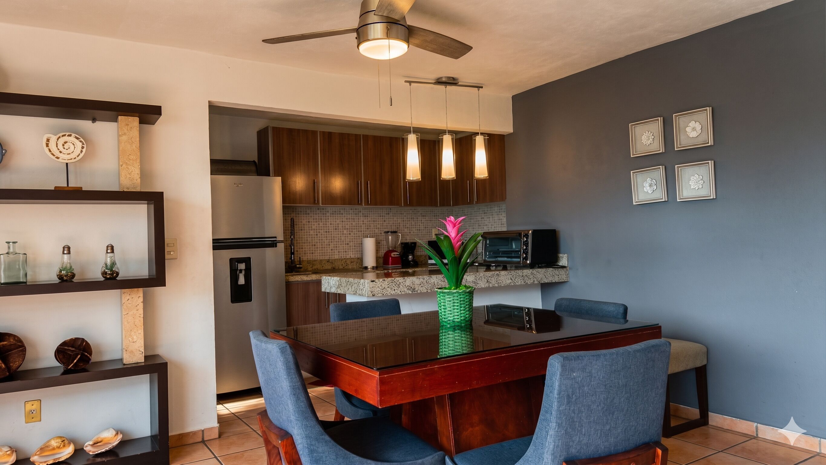 A modern kitchen with a dining area, including a refrigerator, microwave, and a ceiling fan.