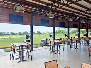 An outdoor covered area with tables and chairs, a view of a golf course, and a wooden ceiling structure. - 4BR 3Bath Pool Home with Golf Course View, Quiet Cul De sac in Southern Dunes (Haines City)
